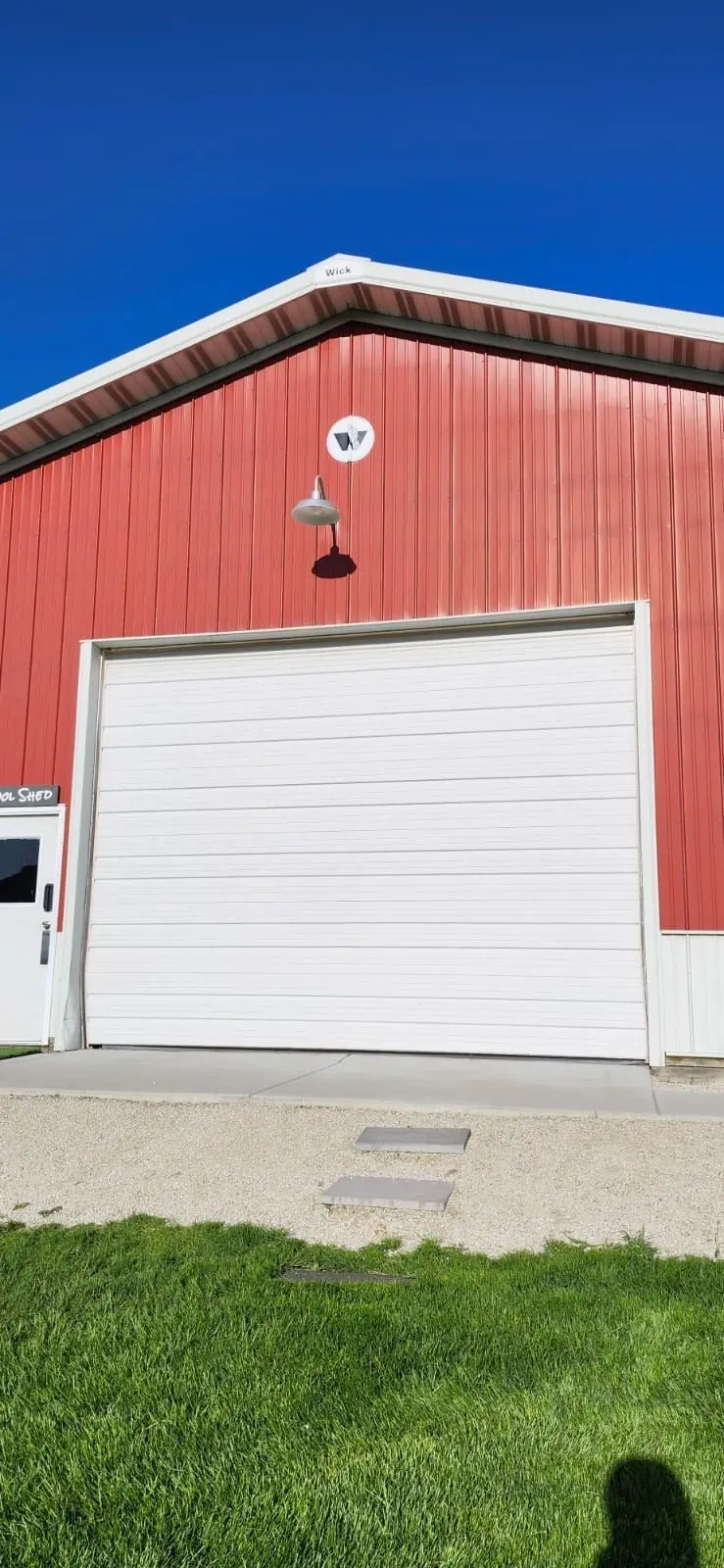 New white sectional door on a red metal building