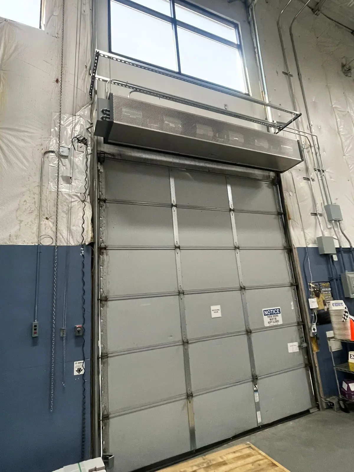 Tall commercial sectional door inside a shop building