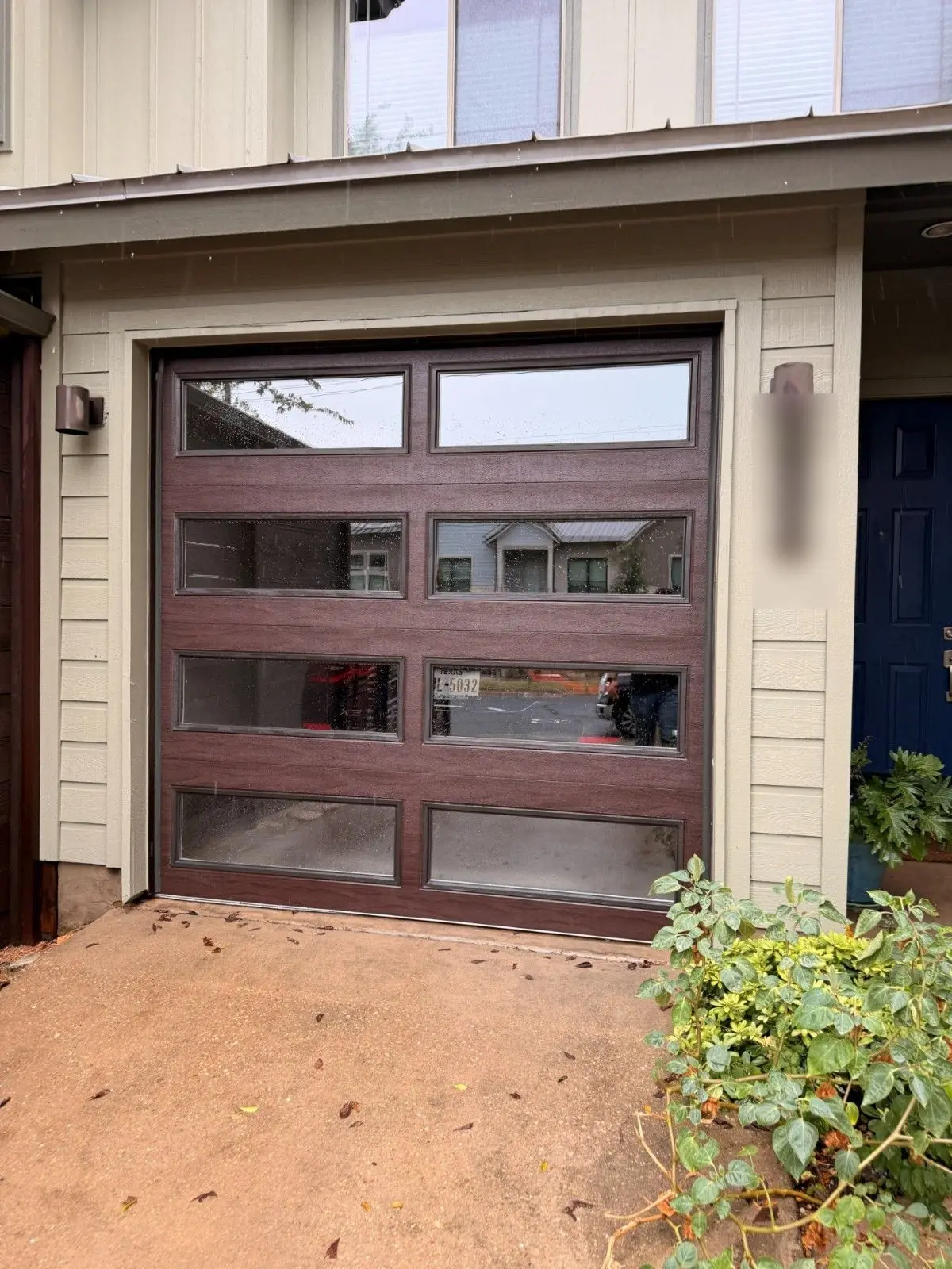 Wood tone framed full view glass garage door on a townhome