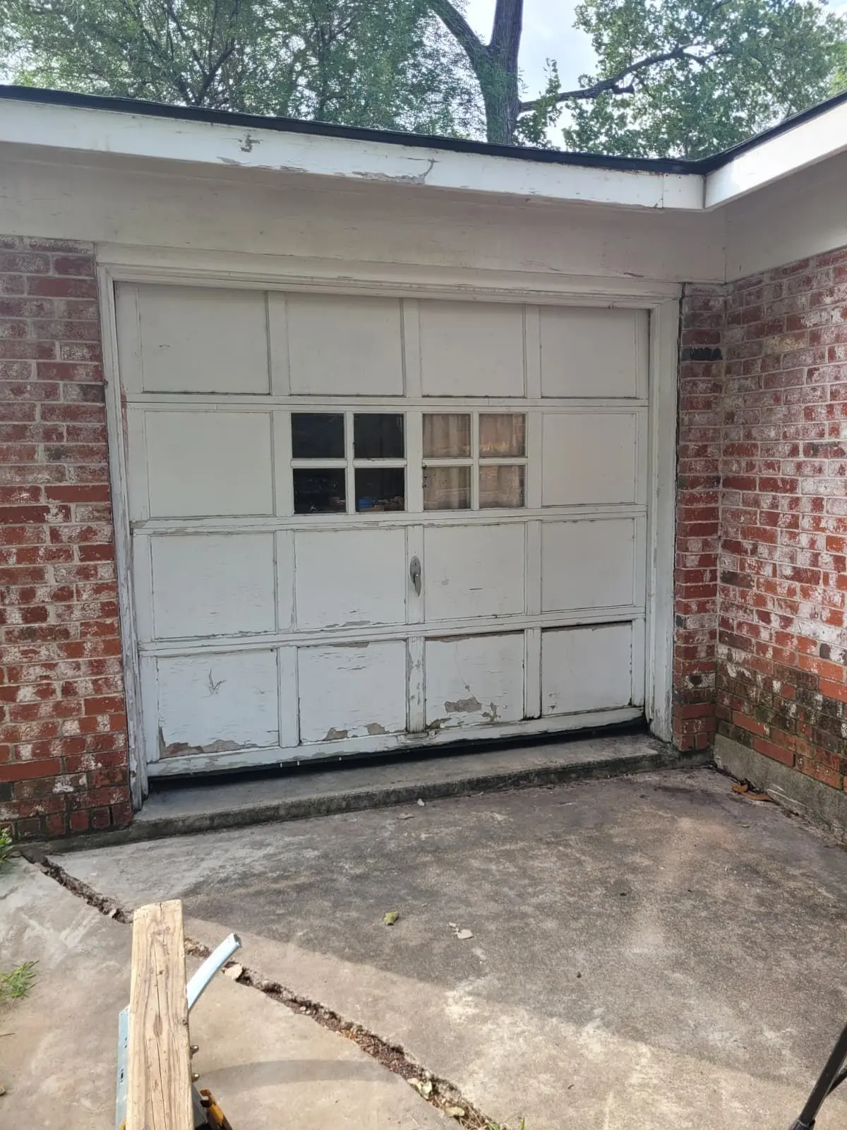 Before: old white single garage door with peeling paint on a brick South Austin home