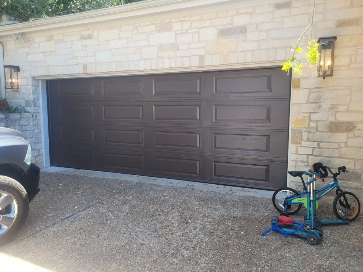 Dark brown raised panel double garage door on a limestone home, installed by Tier One