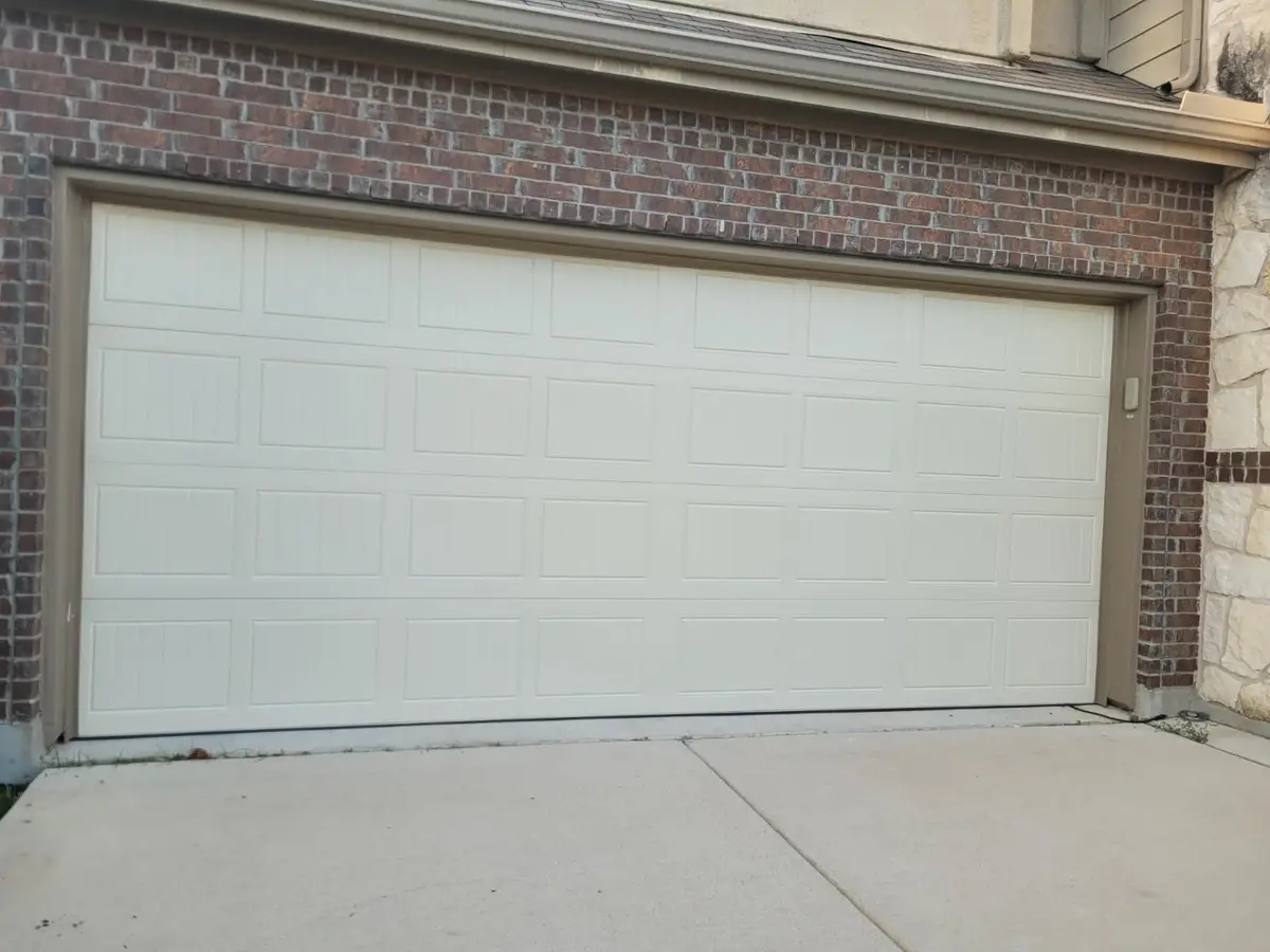 Almond grooved panel double garage door installed by Tier One on a brick Hutto home