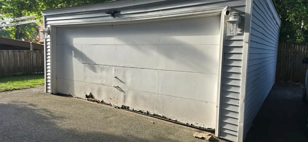 Before: white garage door with dented lower panels