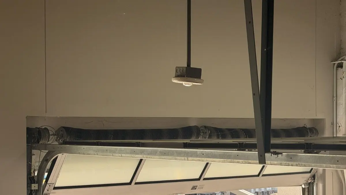 Garage door hanging at an angle from its tracks, seen from inside the garage