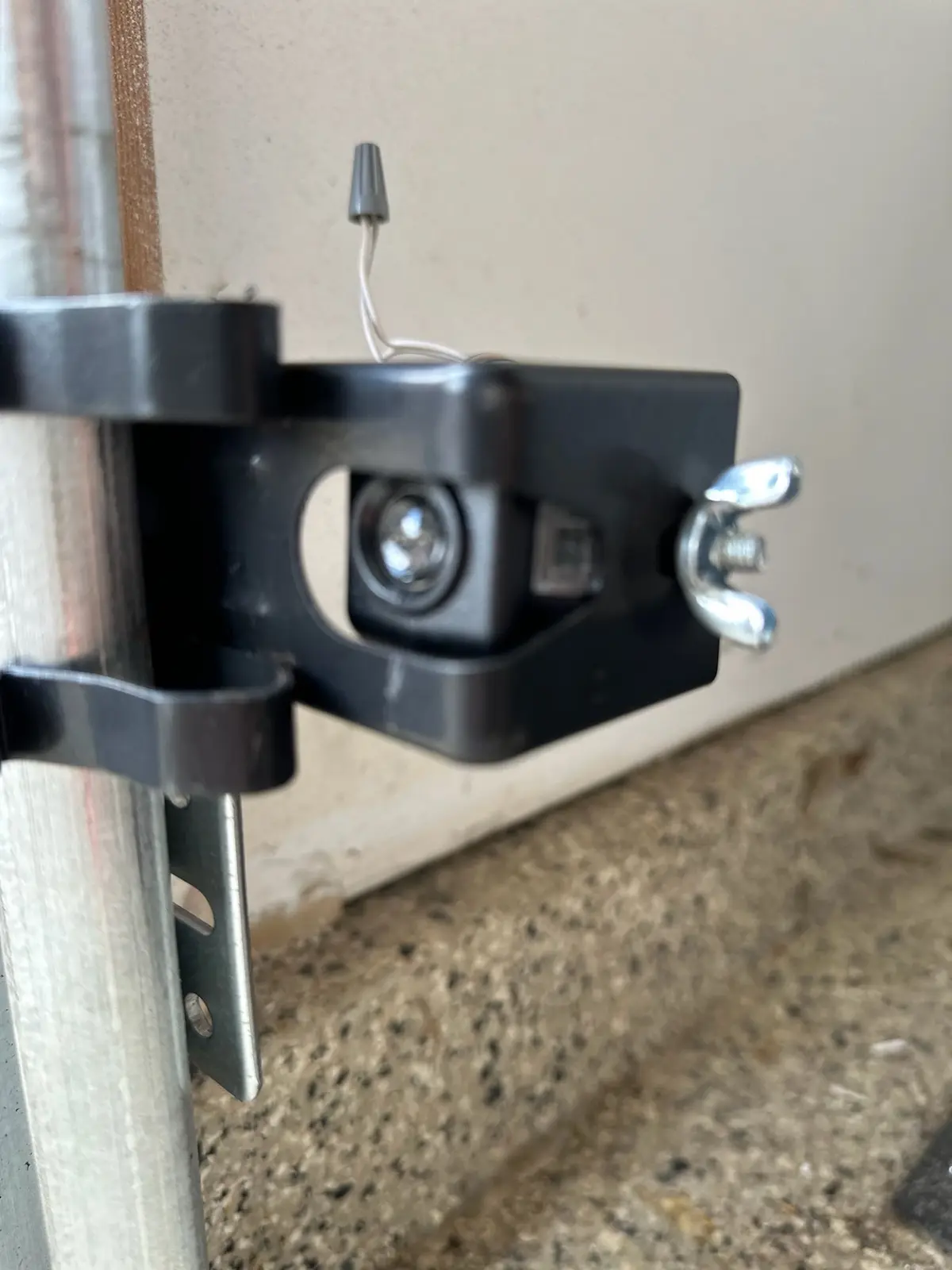 Garage door safety sensor mounted on a bracket beside the track near the floor