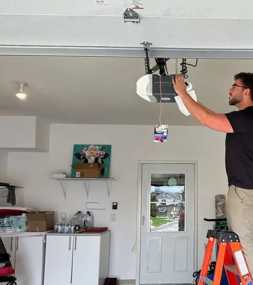 Technician on a ladder working on a garage door opener