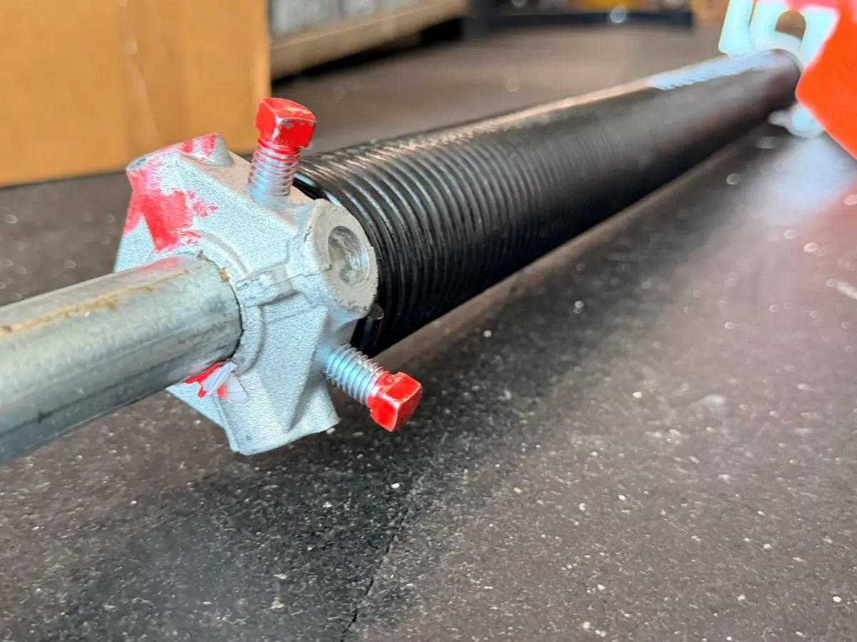 Close-up of a garage door torsion spring and its winding cone with red set screws